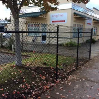 Black vinyl-coated chain link fence with gate at commercial property in Eugene